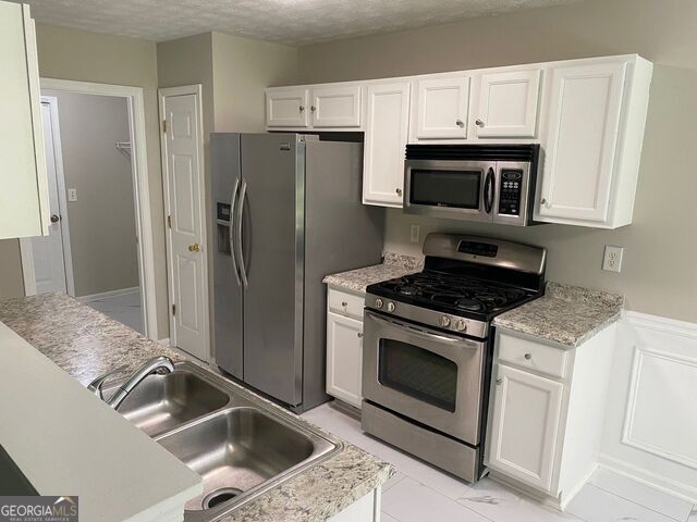 646 Lakes Circle Lithonia, GA 30058 - Photo 7 of 32 a kitchen with granite countertop a sink stove and refrigerator