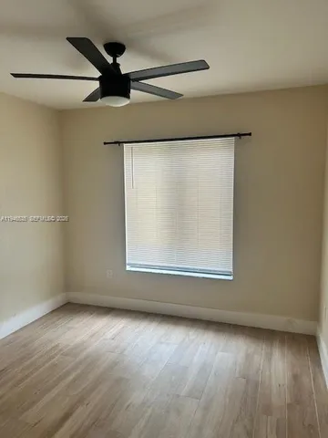 an empty room with wooden floor cabinet and windows