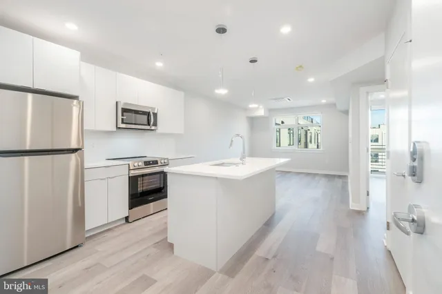 a large white kitchen with a refrigerator stove and a sink
