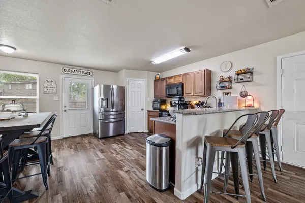 a living room with stainless steel appliances kitchen island granite countertop furniture and wooden floor