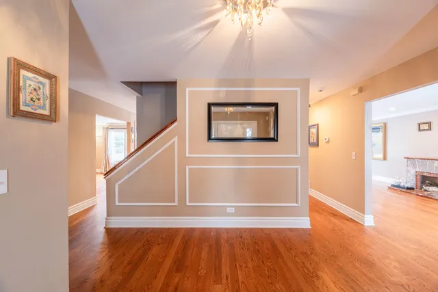 a view of an empty room with wooden floor and a ceiling fan