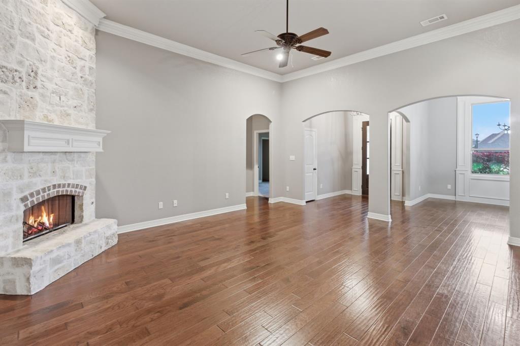 7765 Hickory Spring Lane Tyler, TX 75703 - Photo 14 of 38 Spacious living area featuring a stone fireplace with a white mantel, wood-finish flooring, recessed lighting, and multiple arched doorways