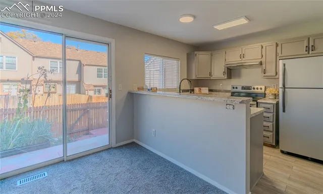 a kitchen with stainless steel appliances granite countertop a refrigerator a sink a stove and white cabinets with wooden floor