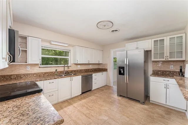 a kitchen with granite countertop a sink stainless steel appliances and cabinets