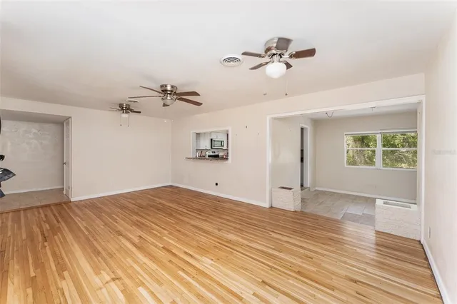 a view of empty room with wooden floor and ceiling fan