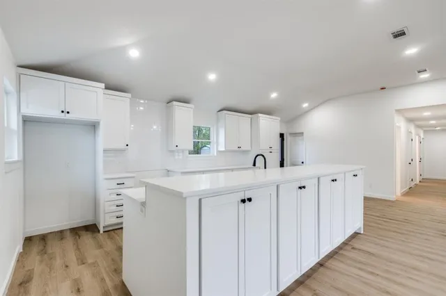 a kitchen with white cabinets and sink