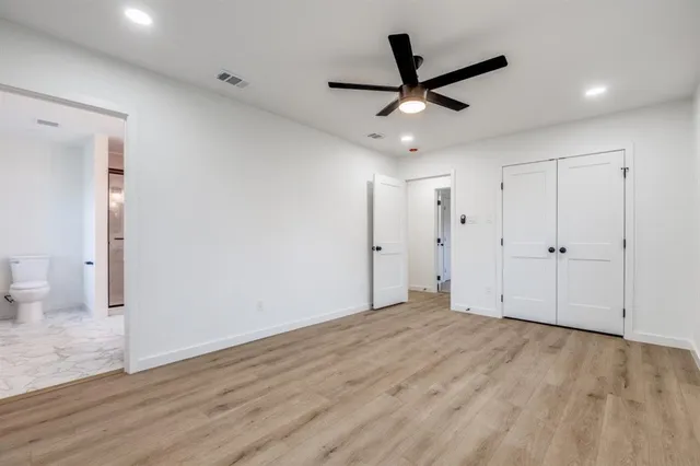 an empty room with wooden floor ceiling fan and window