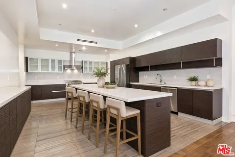 a kitchen with stainless steel appliances kitchen island granite countertop a table chairs sink and cabinets