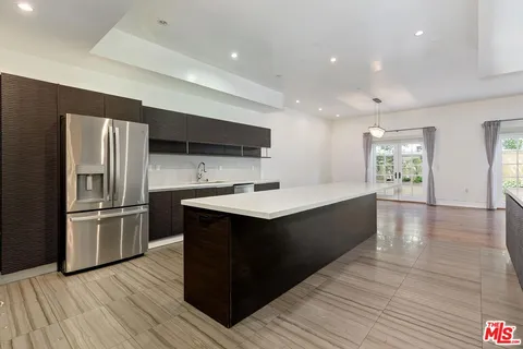a large kitchen with a large counter top stainless steel appliances and wooden floor