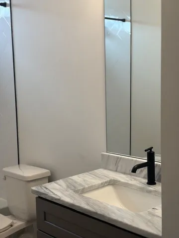 a bathroom with a granite countertop sink toilet and a mirror