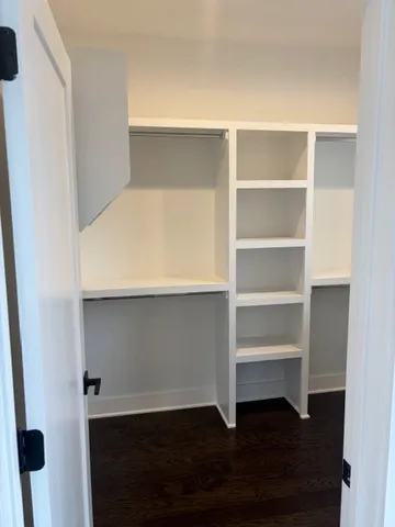 a living room with a wooden floor and shelf