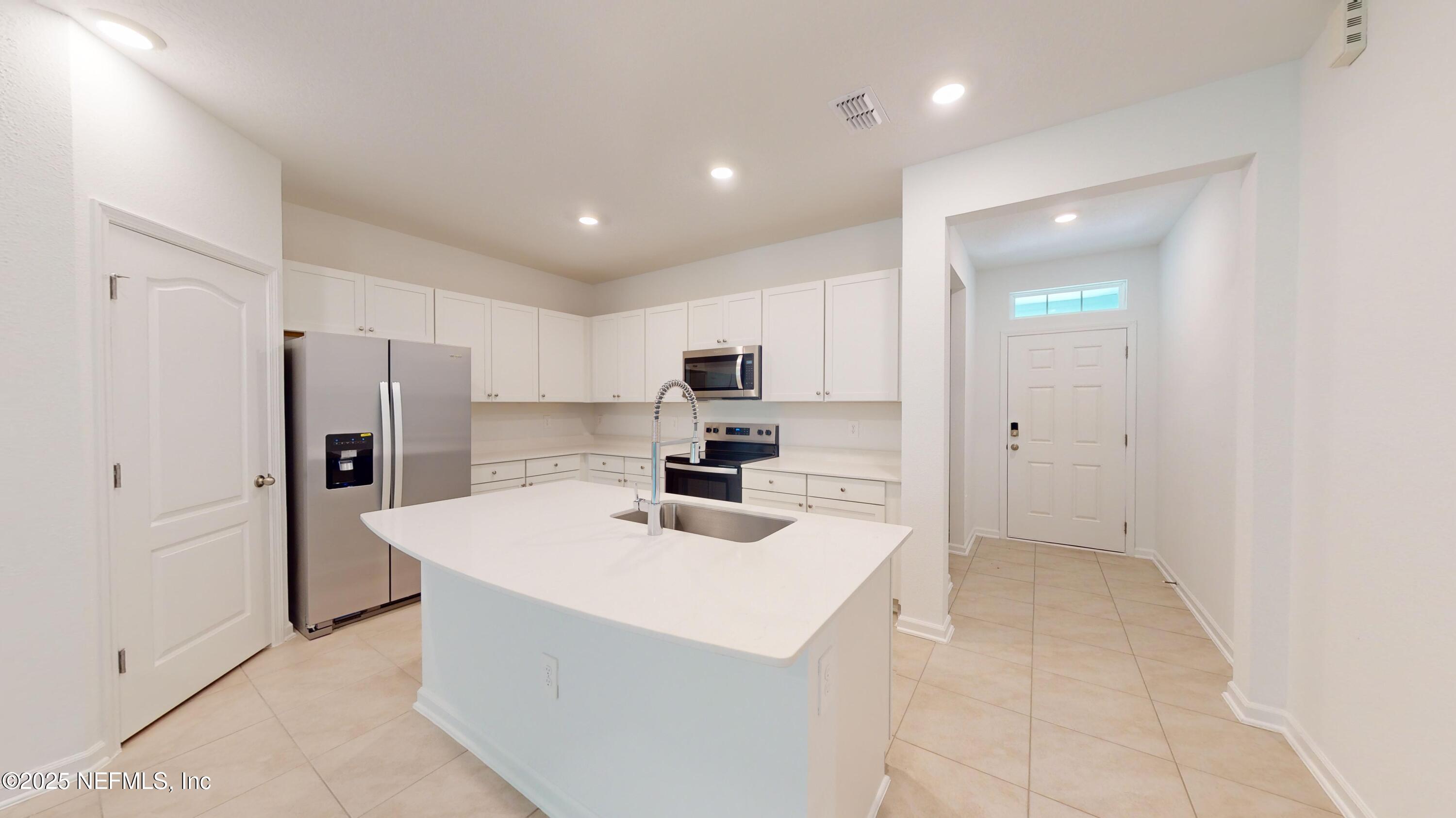 169 Seaport Breeze Road St. Augustine, FL 32095 - Photo 6 of 21 a kitchen with a sink a refrigerator and a stove top oven with white cabinets