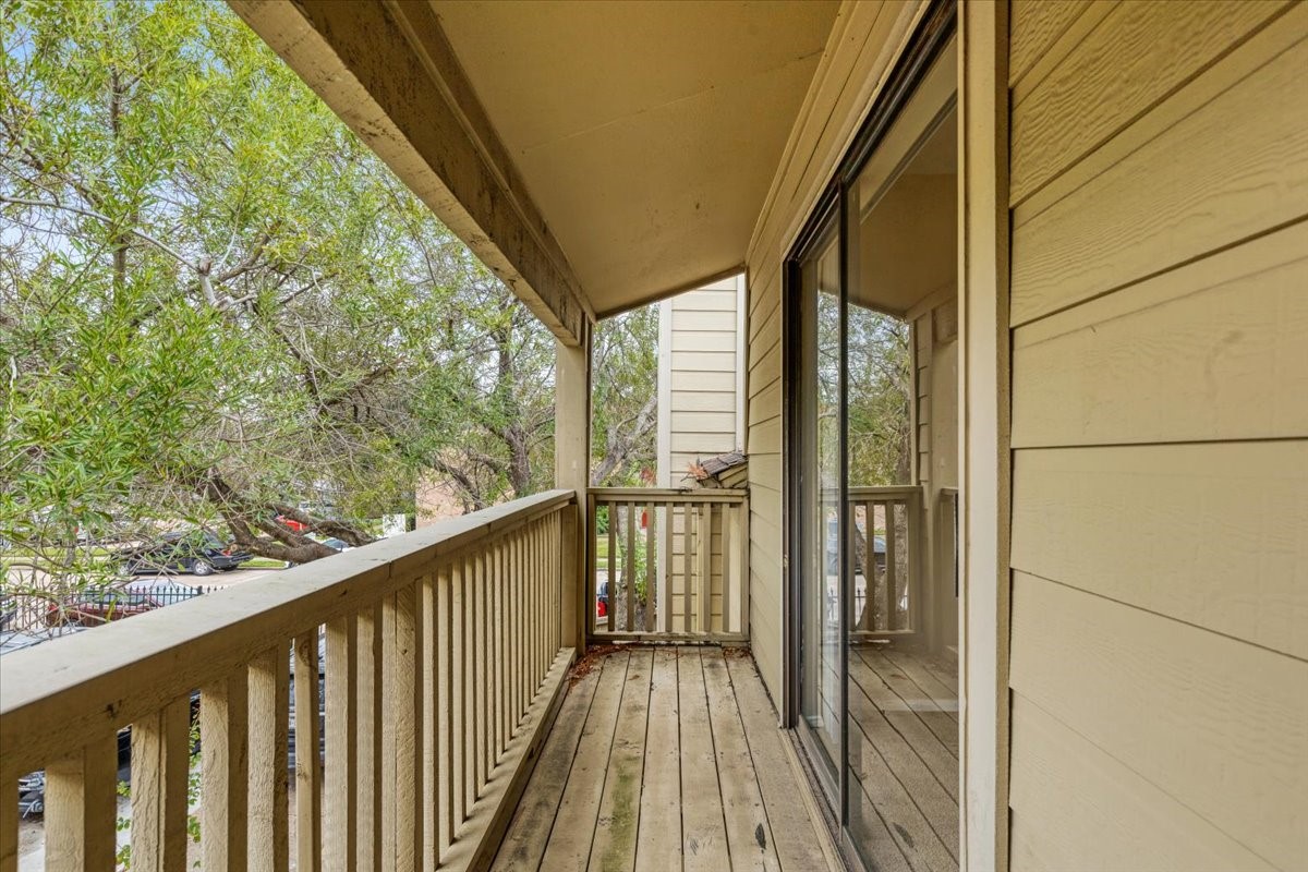 3502 Ocee Street, Unit 3502 Houston, TX 77063 - Photo 22 of 28 Charming wooden balcony with a slanted roof, offering an inviting space adjacent to sliding glass doors. Surrounded by lush greenery, it provides a serene view, perfect for relaxation or enjoying morning coffee.