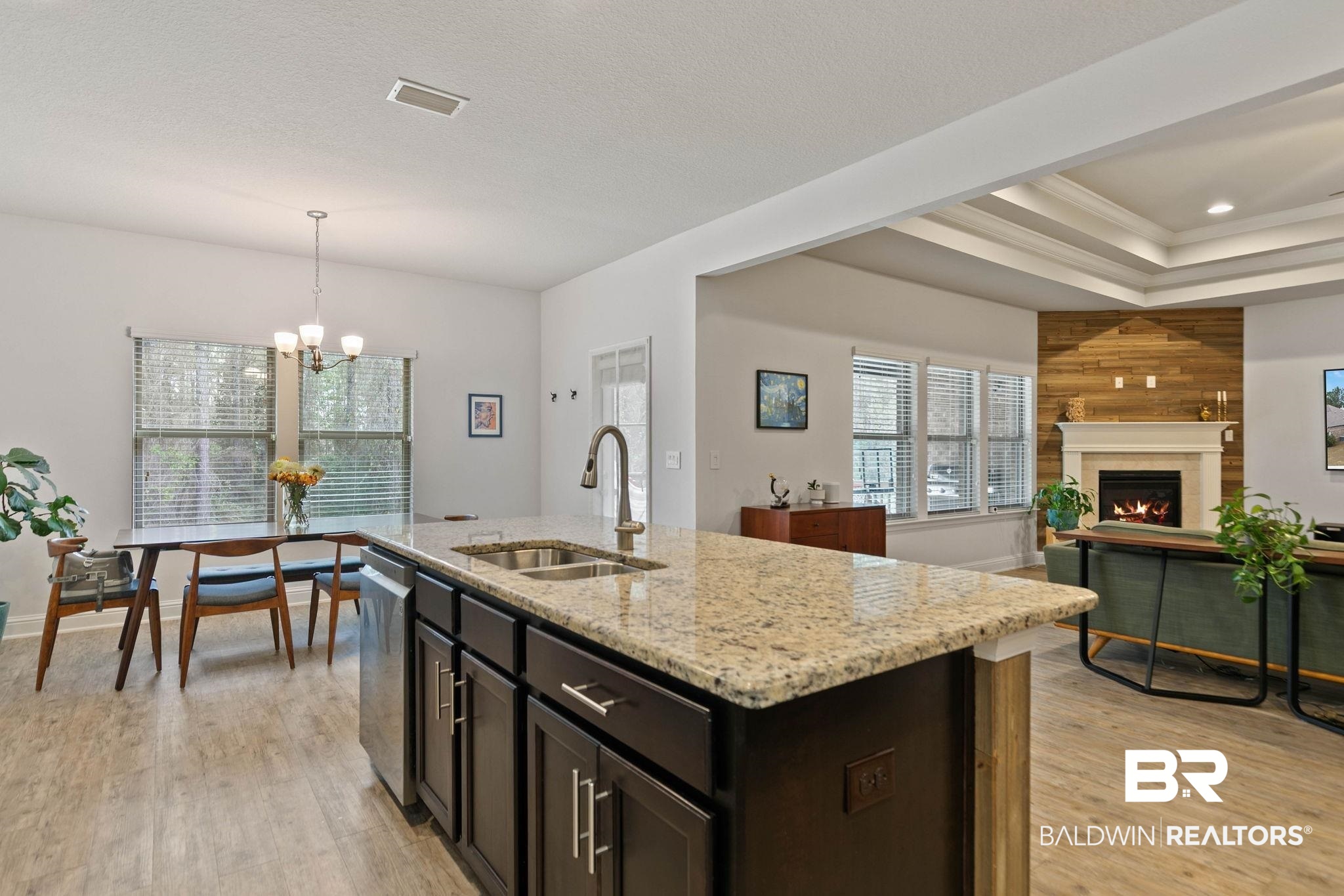 31350 Hoot Owl Road Daphne, AL 36527 - Photo 16 of 94 Kitchen featuring dark wood finish cabinets, light wood-style flooring, light stone counters, a tray ceiling, and crown molding