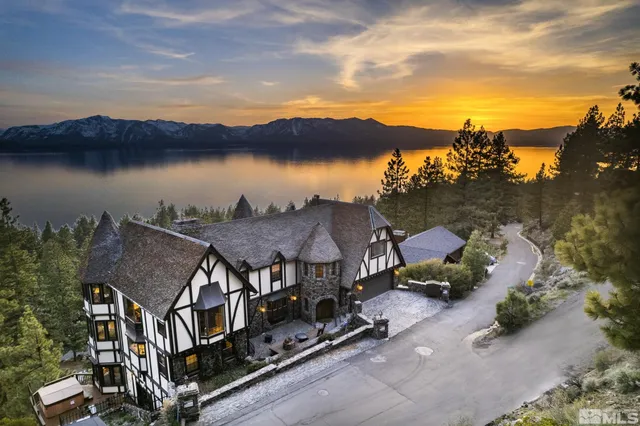 an aerial view of a house with lake view and a mountain view in back