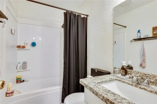 a bathroom with a granite countertop sink a toilet and shower
