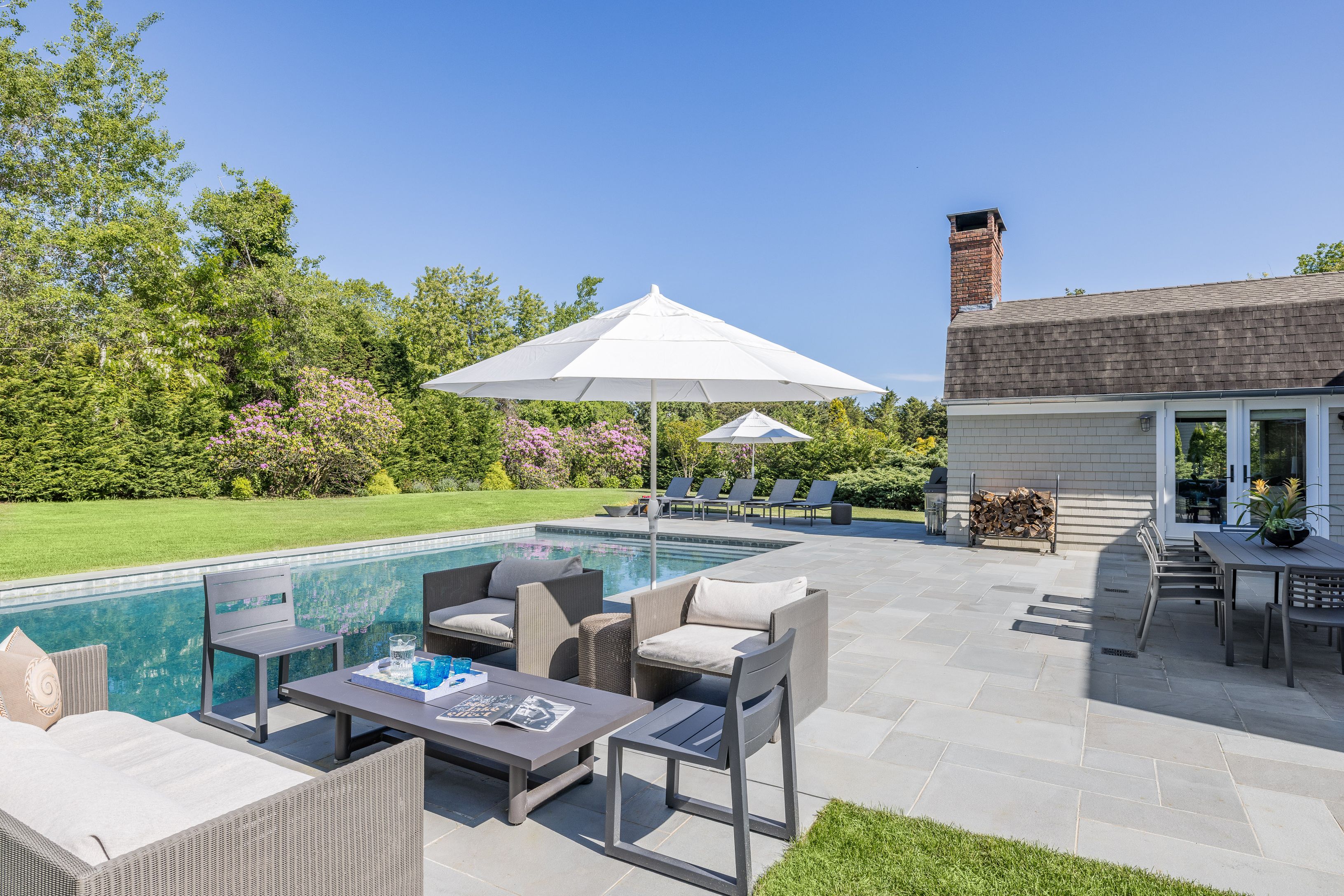 a patio with tables and chairs pool and a fire pit with the wooden fence