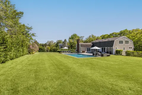a view of a house with a big yard potted plants and large tree