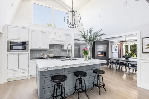 a kitchen with stainless steel appliances granite countertop a stove top oven a refrigerator a dining table and chairs with wooden floor