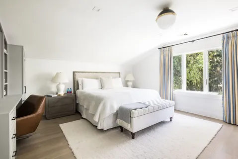 a spacious bedroom with a bed lamp and a large window