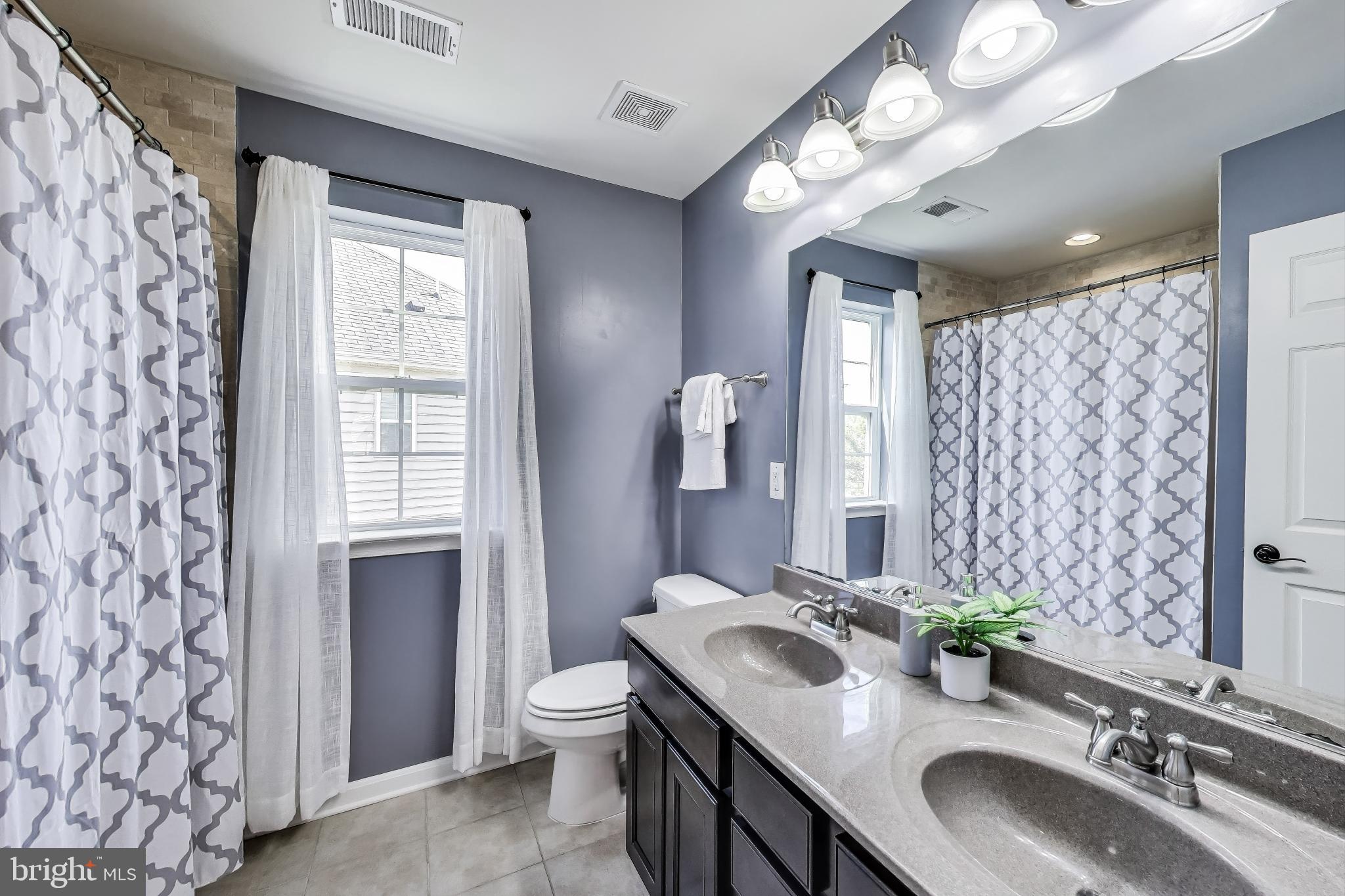 5701 Wink Way Woodbridge, VA 22193 - Photo 27 of 45 a bathroom with double vanity sink a toilet a shower and a large mirror