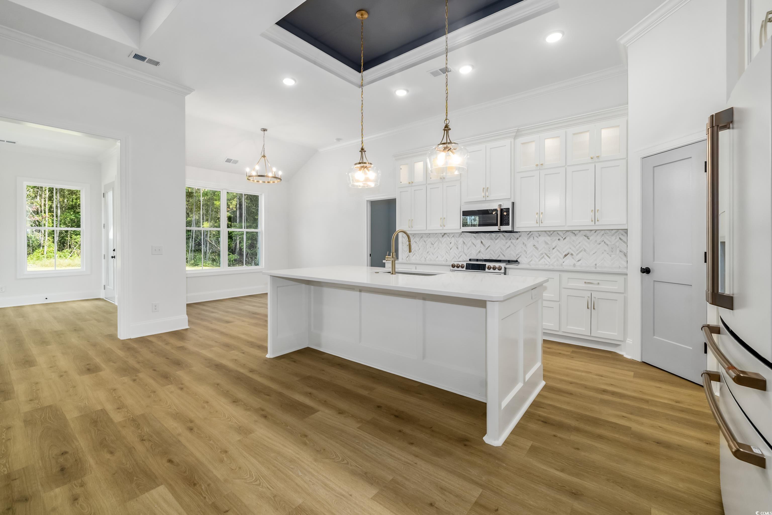 346 Ridge Road Galivants Ferry, SC 29544 - Photo 5 of 24 Kitchen featuring backsplash, a kitchen island with sink, hanging light fixtures, glass insert cabinets, and white appliances