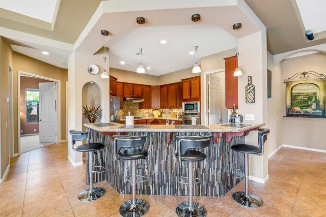 a view of a kitchen with kitchen island granite countertop lots of wooden cabinets a dining table and chairs