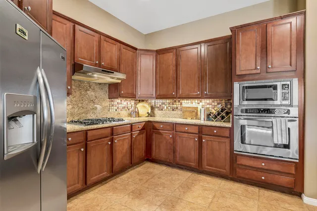 a kitchen with granite countertop wooden cabinets stainless steel appliances and a window