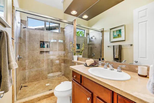 a bathroom with a granite countertop sink a toilet a mirror and shower