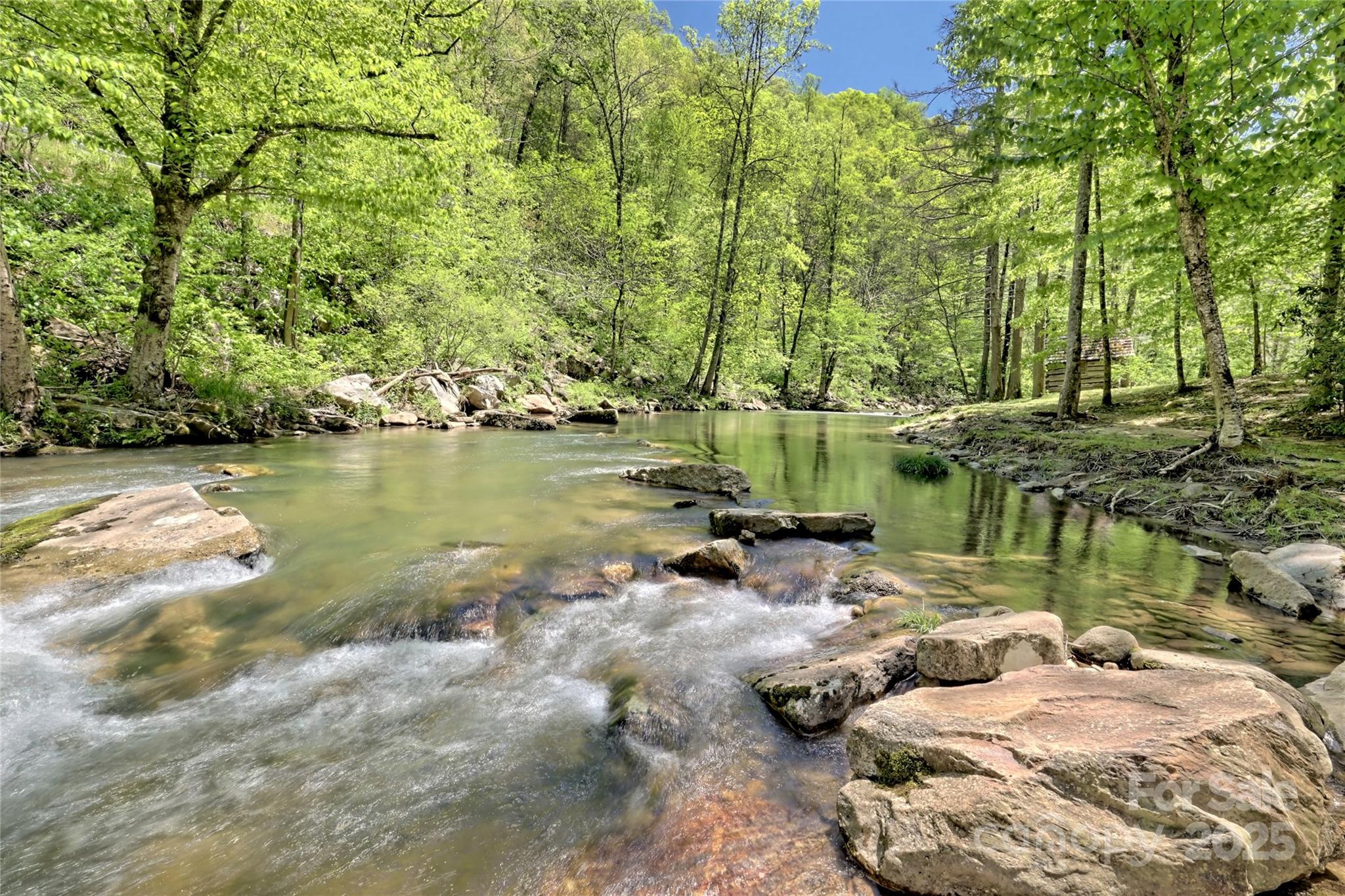 Lot 13 Hares Ear Lane, Unit 13 Cullowhee, NC 28723 - Photo 12 of 23 a view of a lake with lawn chairs and large trees