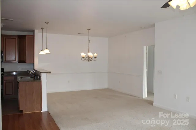 a view of a room with a chandelier fan and wooden floor