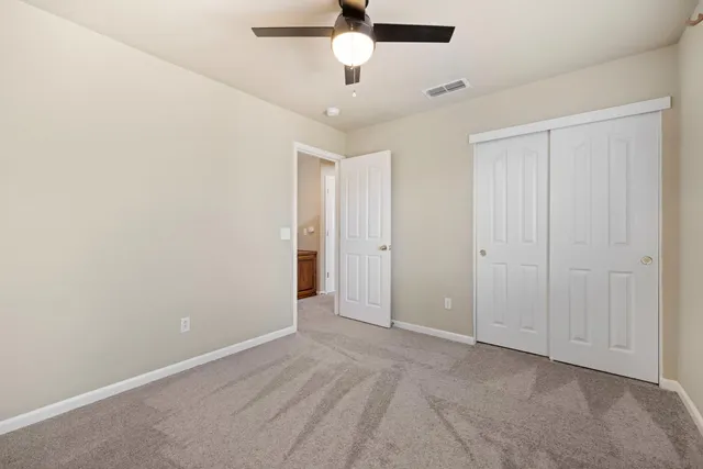 an empty room with a ceiling fan and carpet