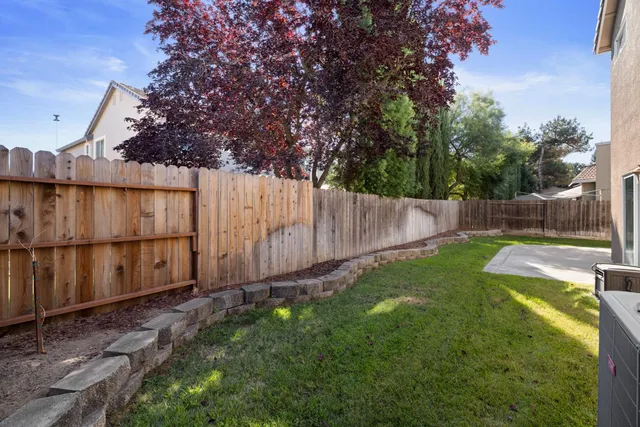 a view of backyard with wooden fence and large trees