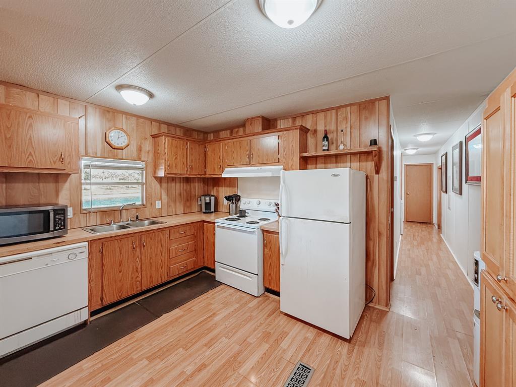 128 Meandering Way Mabank, TX 75156 - Photo 24 of 38 a kitchen with a refrigerator a sink and dishwasher wooden cabinets with wooden floor