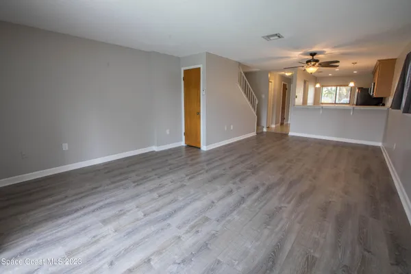 a view of a big room with wooden floor and a kitchen