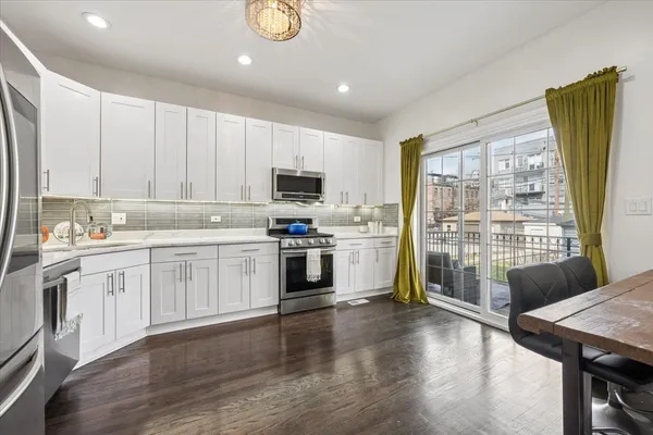 a kitchen with granite countertop wooden floors stainless steel appliances and sink