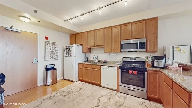 a kitchen with stainless steel appliances granite countertop a stove top oven a sink dishwasher and a refrigerator