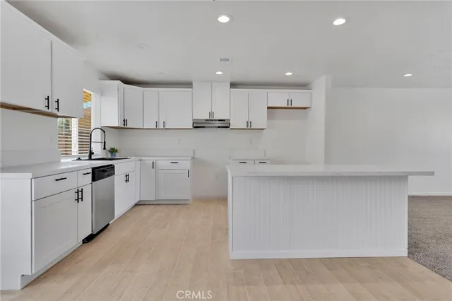 a kitchen with white cabinets appliances and a window