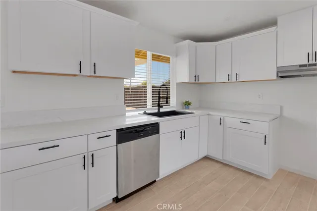 a kitchen with white cabinets appliances a sink and a window