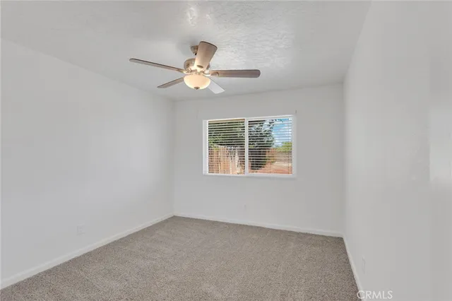 an empty room with a window and a fan