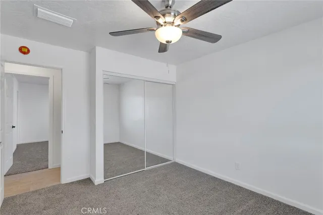 an empty room with a ceiling fan and carpet
