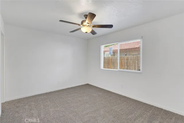 an empty room with windows and chandelier fan