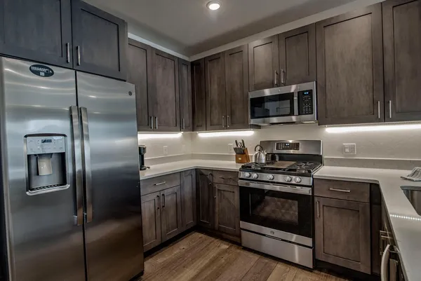 a kitchen with cabinets stainless steel appliances and wooden floor