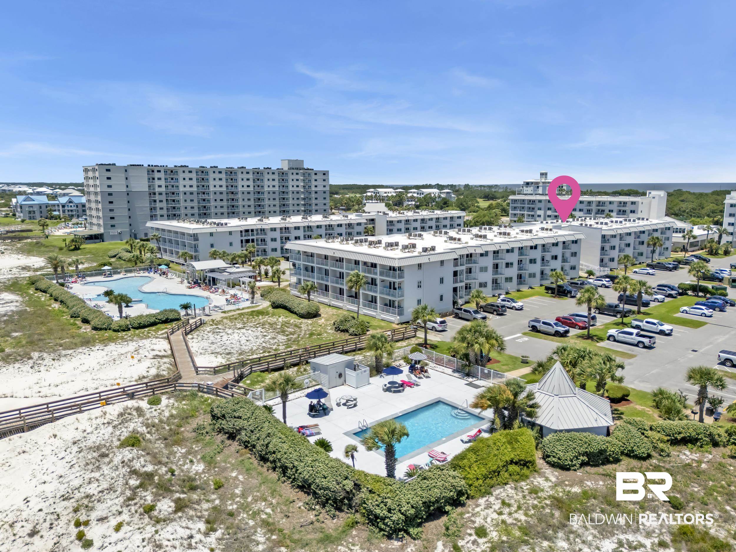400 Plantation Road, Unit 2118 Gulf Shores, AL 36542 - Photo 1 of 59 Aerial perspective of a multi-building complex featuring multiple swimming pools, extensive parking areas, and a wooden boardwalk system traversing sandy terrain