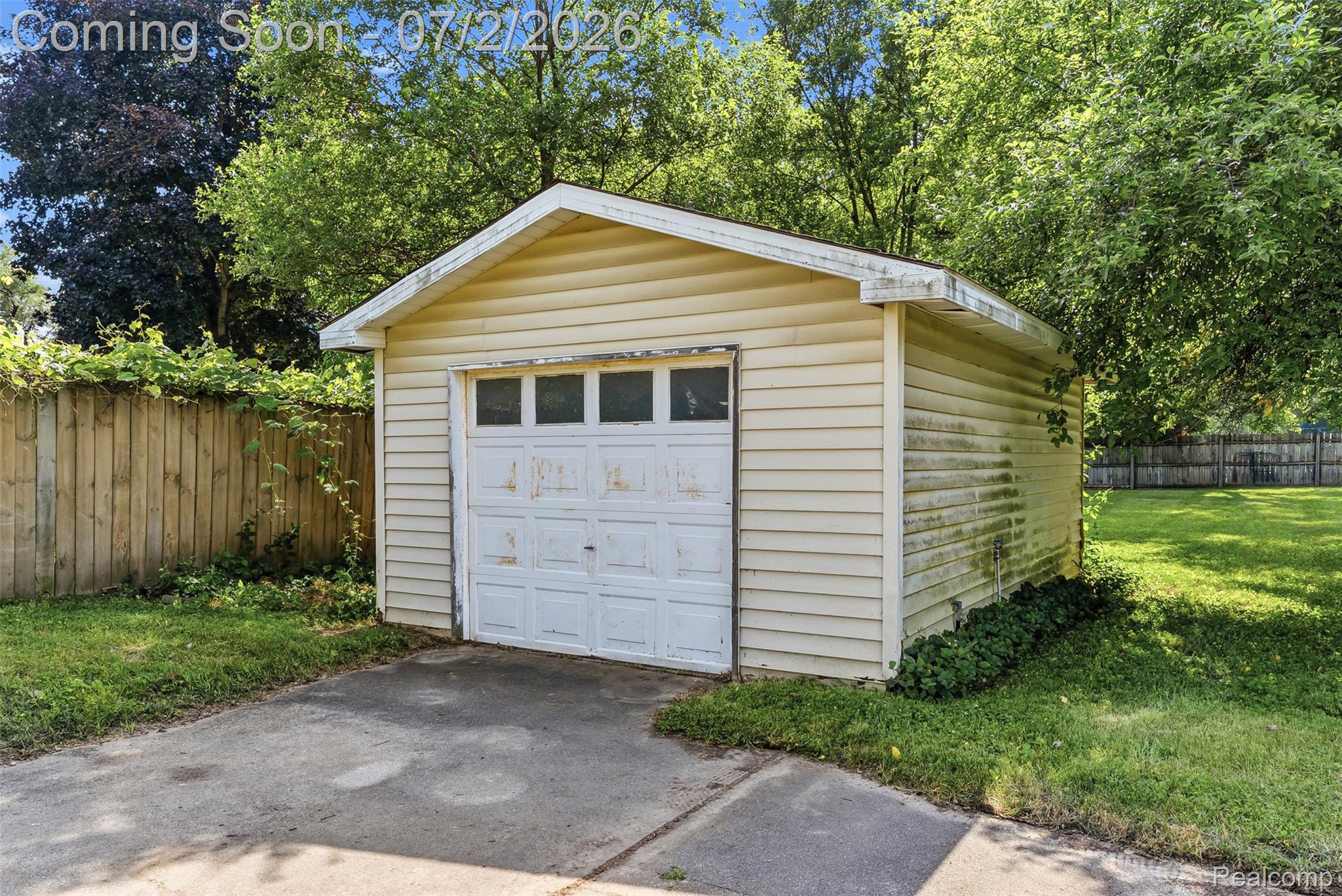 305 East Road Holly, MI 48442 - Photo 36 of 41 Detached garage with vinyl siding and a panel garage door, featuring a concrete driveway and surrounding green lawn