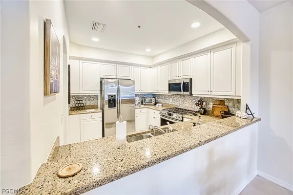 a view of a kitchen with kitchen island a sink appliances and cabinets