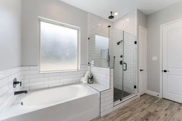 a bathroom with a tub shower sink and mirror