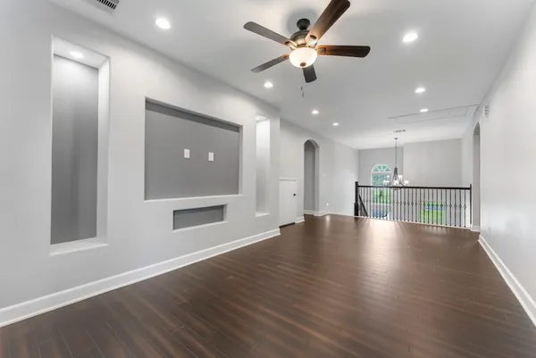 an empty room with wooden floor and windows