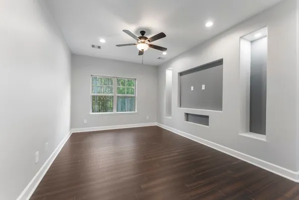 a view of an empty room with wooden floor and a window