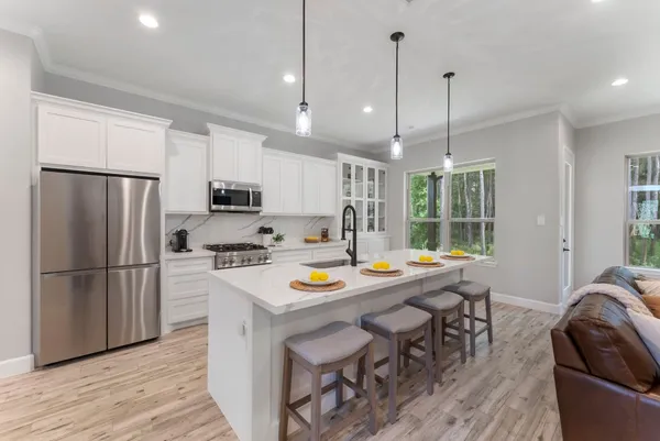 a kitchen with stainless steel appliances granite countertop a refrigerator a sink a stove a refrigerator a dining table and chairs